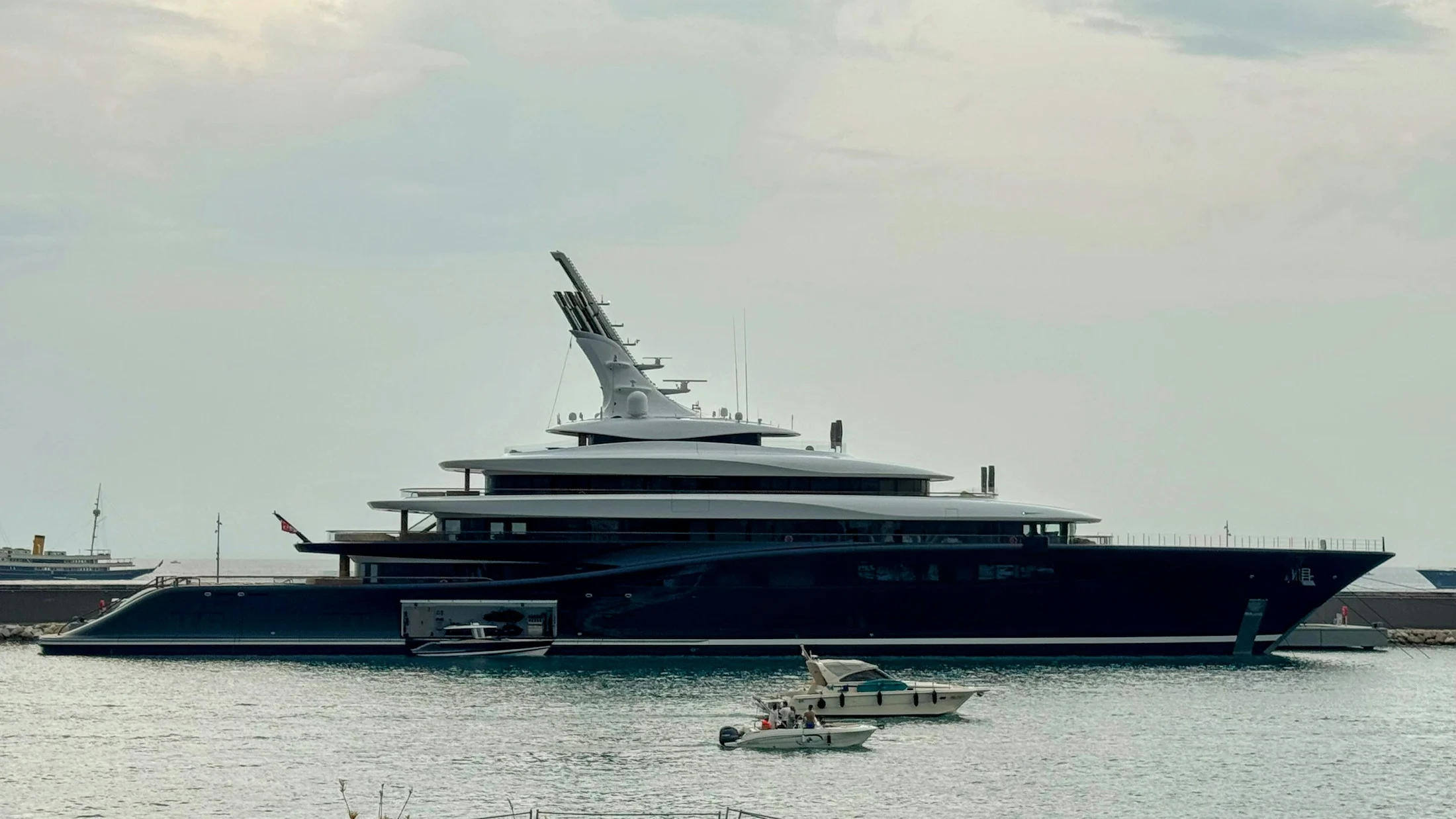 Photograph of a dark blue motor yacht berthed in a harbor